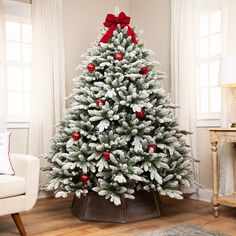 a decorated christmas tree in a living room with red and white ornaments on the top