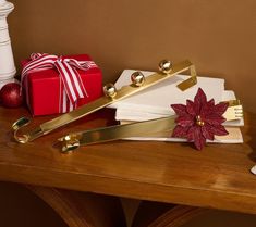 a wooden table topped with christmas decorations and wrapping paper next to a red present box