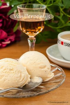 two scoops of ice cream sit on a glass plate next to a cup of tea