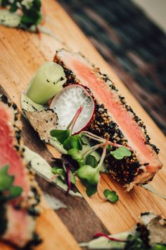 a wooden cutting board topped with slices of food and veggies on top of it