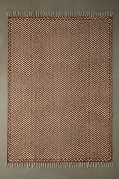 a brown and white rug with fringes on the floor in front of a wall