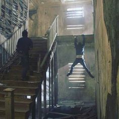 a man is jumping down the stairs in an abandoned building while another person watches him