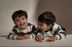 two young boys laying on the ground with their mouths open