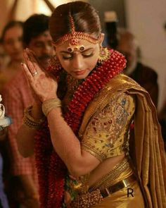 a woman in a red and gold sari holding her hands together