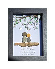 a photo frame with rocks and flowers on it, in the shape of a tree branch