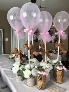 there are some teddy bears in mason jars on the table with flowers and balloons attached to them