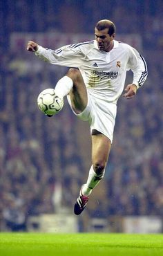 a man kicking a soccer ball on top of a field