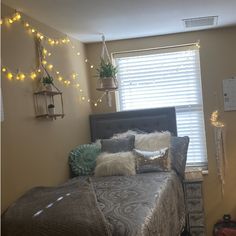 a bed room with a neatly made bed and some lights on the window sill