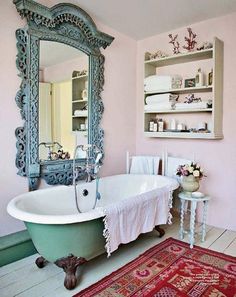 a bath tub sitting next to a mirror in a bathroom on top of a rug