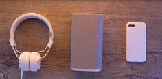 an iphone case, headphones and book on a wooden table with ear phones next to it