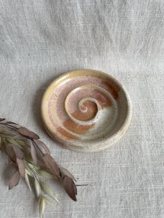 a small bowl sitting on top of a table next to a dried plant in front of it