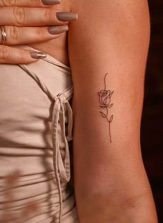 a woman's arm with a small rose tattoo on the left side of her arm