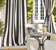 black and white striped curtains hanging in front of a window with a table next to it