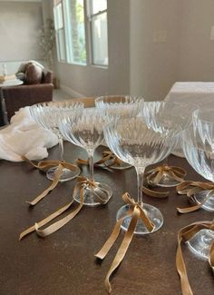 there are many wine glasses on the table with gold ribbons around them and one is empty