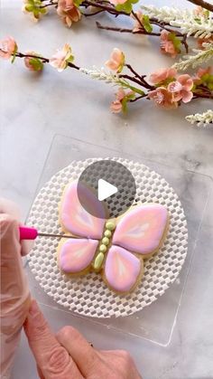 someone is decorating some cookies with icing and flowers on the table next to them