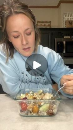 a woman sitting at a table with a bowl of food in front of her and spoon