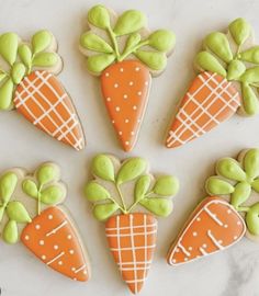 decorated cookies with carrots and green icing on a white countertop, top view