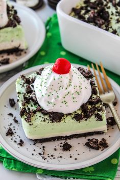 there is a piece of cake on the plate with whipped cream and green sprinkles