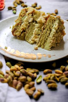 a white plate topped with two pieces of cake next to pistachios on a table