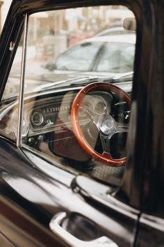 an old car with a steering wheel in it's dash board and dashboard, seen through the window