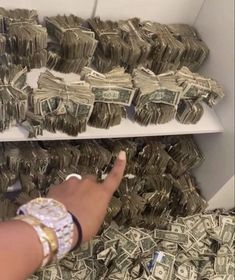 a person pointing at stacks of money on a shelf