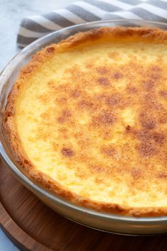 a cheese pie sitting on top of a wooden table next to a knife and fork