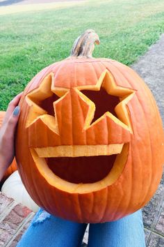 a person holding a carved pumpkin in their hands