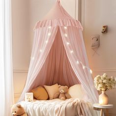 a pink canopy bed with teddy bears on the bottom and pillows underneath it, in a girls'bedroom