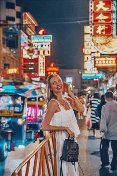 a woman standing on the side of a street next to neon signs