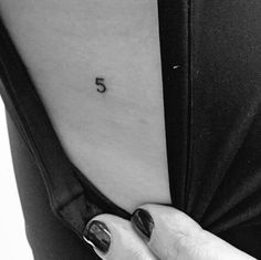 a woman's stomach with the number five tattooed on her lower back and upper arm