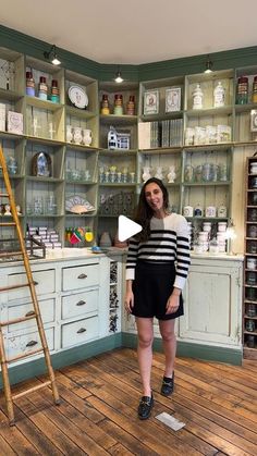 a woman standing in front of a shelf filled with dishes