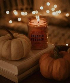 a candle sitting on top of a book next to two pumpkins