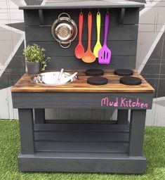 an outdoor kitchen with pots and pans on the stove top, utensils hanging from hooks