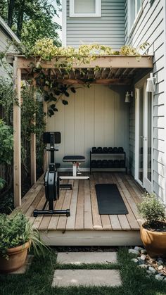 an outdoor gym area with exercise equipment in the back yard, surrounded by greenery and potted plants