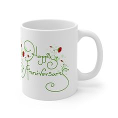 a white coffee mug with the words happy anniversary printed on it and flowers in green