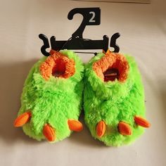 a pair of green fuzzy slippers hanging on a clothes hanger with the number two