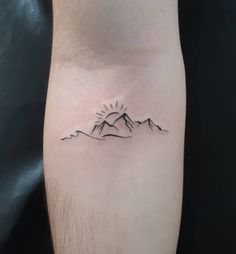 a man's arm with a small mountain tattoo on it