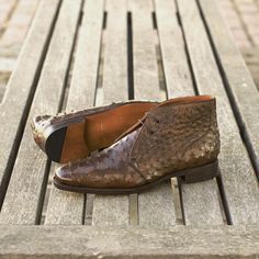 a pair of brown shoes sitting on top of a wooden bench