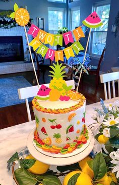 there is a cake on the table with fruit and bunting flags in front of it