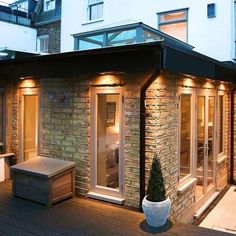 an outdoor patio with lights on and a potted tree in the corner next to it