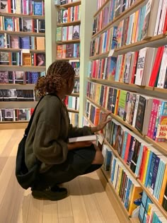 a woman sitting on the floor in front of a book shelf filled with lots of books