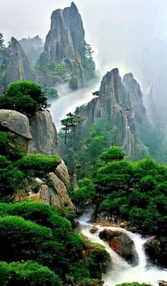 the mountains are covered in green trees and rocks, with water running between them on either side