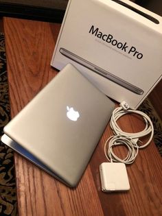 an apple macbook pro sitting on top of a table next to a charger