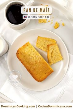 two pieces of cornbread on a white plate next to a cup of coffee