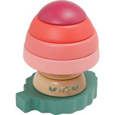 a pink and green toy on top of a wooden stand with an object in the middle