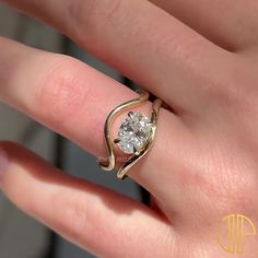 a woman's hand with a gold ring and a diamond in the shape of a heart