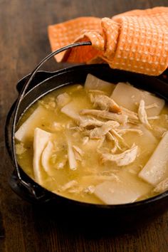 chicken and dumpling soup in a cast iron skillet on a wooden table with an orange napkin