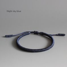 a blue string bracelet on a white surface with the words night sky blue written across it