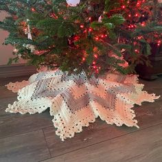 a crocheted christmas tree skirt on the floor next to a decorated christmas tree