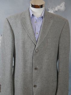 This retro menswear light gray wool Hugo Boss blazer has a notch collar and padded shoulders, and closes in the front with three gray buttons. Four buttons decorate each sleeve edge. The handsome European vintage jacket has two jetted hip pockets and one slanted jetted pocket on the left chest. The blazer is fully lined in a silver satin polyamid-nylon fabric, and has four inner pockets. Chest = 46 inches (116.84cm) (the extra 2 inches here allow for what you wear under) Shoulder Width = 21 inch Gray Winter Sport Coat With Suit Collar, Business Gray Wool Sport Coat, Gray Wool Sport Coat For Business, Gray Tweed Business Jacket, Gray Long Sleeve Tweed Jacket For Business, Classic Gray Winter Sport Coat, Gray Wool Blazer With Lapel Collar, Gray Wool Single Breasted Sport Coat, Classic Gray Wool Blazer